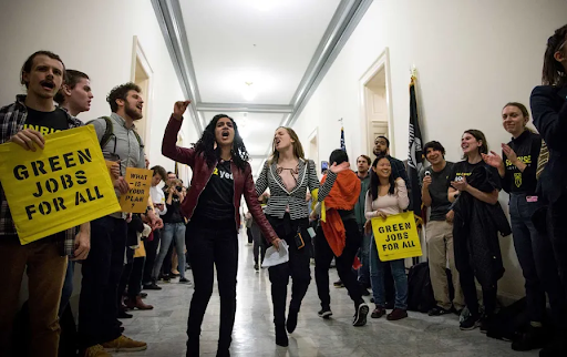 Varshini Prakash and members of the Sunrise Movement in the U.S. Capitol building holding signs that read 'Green Jobs for All'
