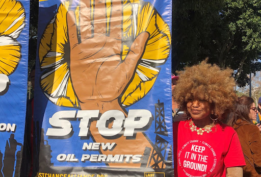 Unique Vance standing next to a large colorful banner that reads 'Stop New Oil Permits'